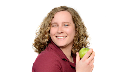 Bex smiling, holding a green apple